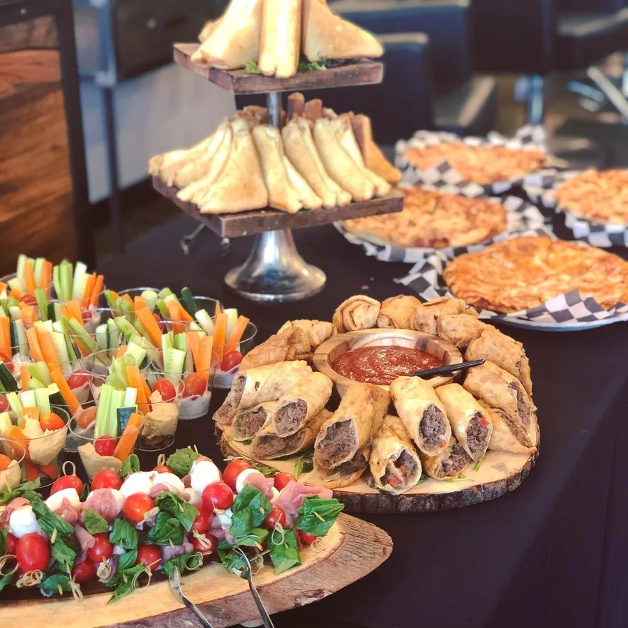 Buffet-style catering spread of appetizers, pizza, and sandwiches