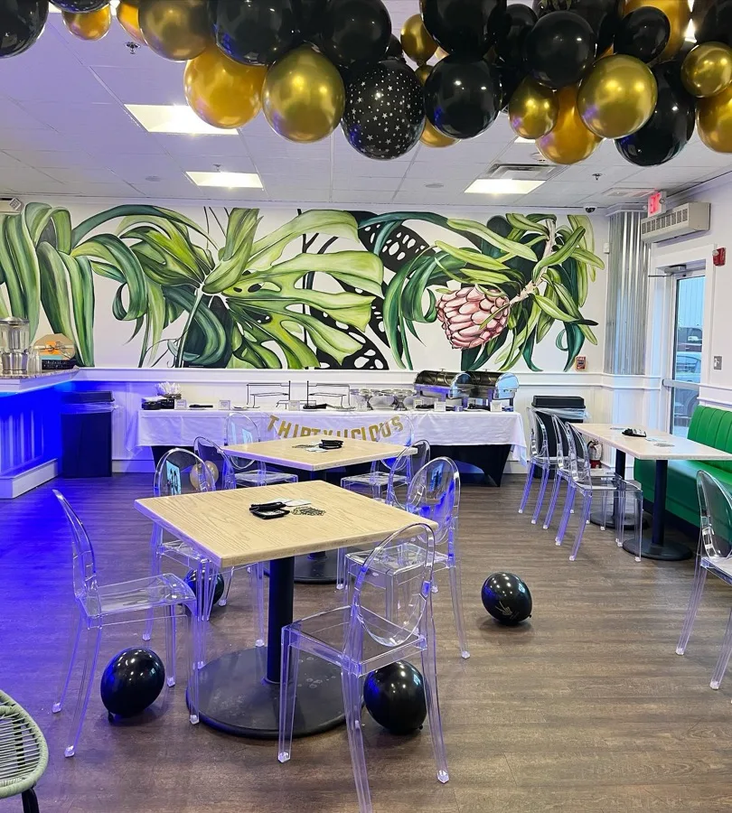 Private function room decorated with a balloon garland and tropical mural